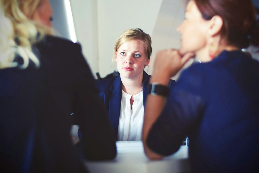 A woman sitting in front of two other women having a job interview