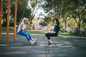 Two friends on swings in a park